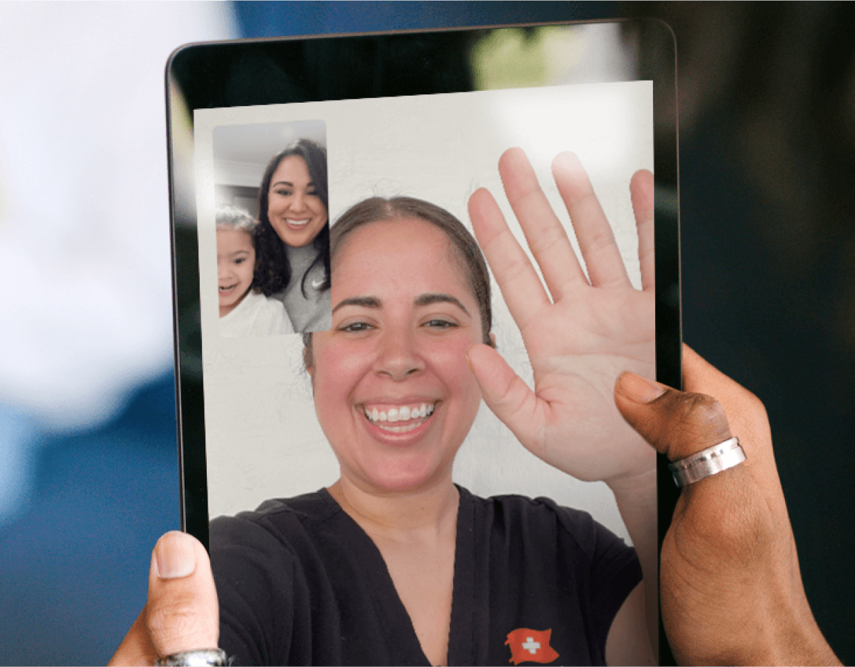 Photograph of hands holding an iPad displaying a telehealth video call between a Brave Care provider and a parent and child