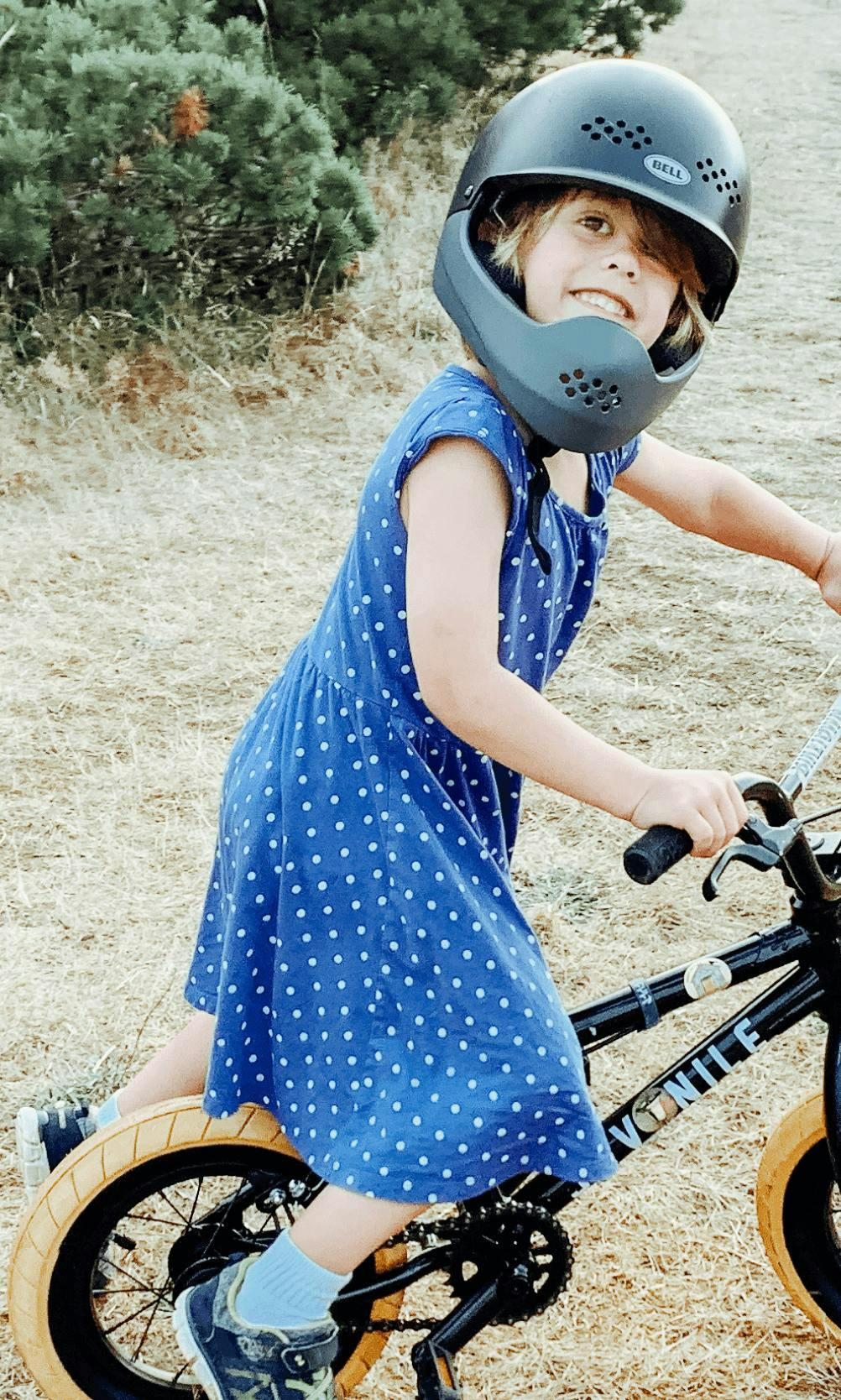 Picture of smiling child wearing a helmet on a bicycle