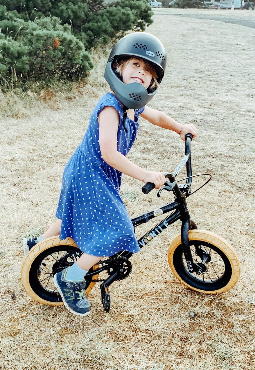 A little girl wearing a helmet while on a bike