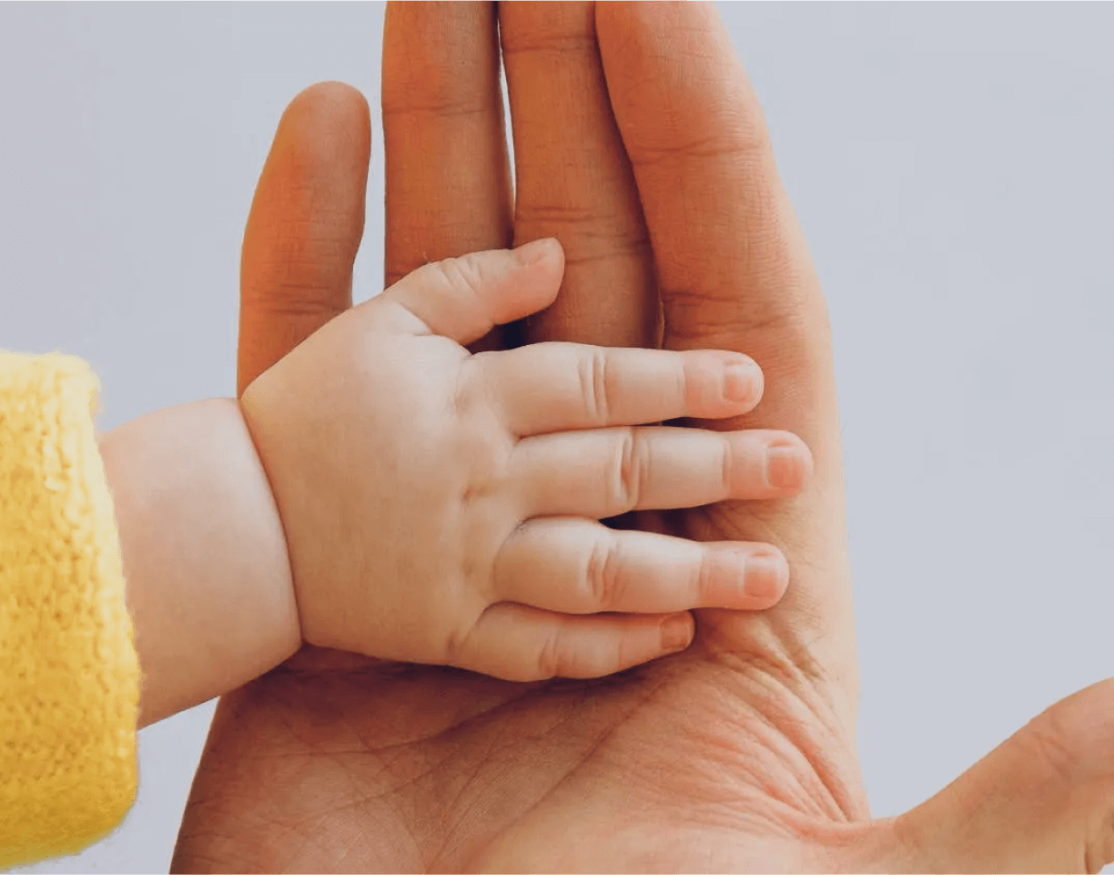 Photo of a parent's hand holding a baby's hand